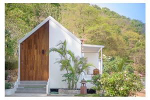 uma pequena casa branca com uma porta de madeira em Seashell Village Resort em Praia de Chao Lao