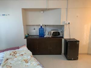 a small kitchen with a microwave and a bed at Kamil’s Studio Apartment in Lucknow