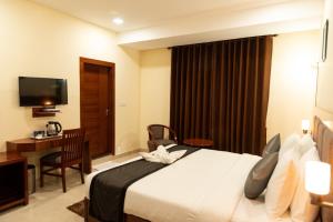 a hotel room with a bed and a desk and a television at Hotel Ballerina in Tinsukia