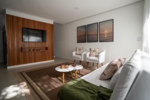 uma sala de estar com um sofá branco e uma televisão em PARAÍSO DO DENDÊ - FLATS em Barra Grande