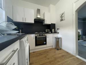 a kitchen with white cabinets and a stove top oven at Raploch House in Larkhall