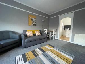 a living room with a couch and a table at Raploch House in Larkhall