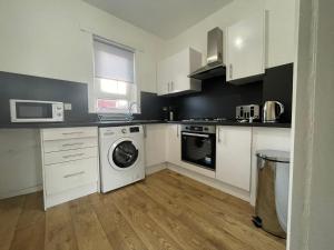 a kitchen with white cabinets and a washing machine at Raploch House in Larkhall