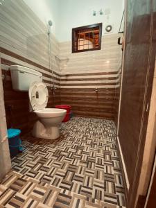a bathroom with a toilet and a tile floor at 3 Hills Hostel in Wayanad