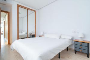 a white bedroom with a large bed and a mirror at SWEET MEDITERRANEAN SUITES - BEACH in Valencia