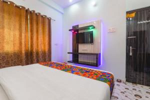 a bedroom with a bed and a tv on the wall at FabHotel Lumbini International - Nr Sarnath Museum in Varanasi