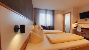 a hotel room with two beds and a desk at Hotel Restaurant Adler in Immenstaad am Bodensee