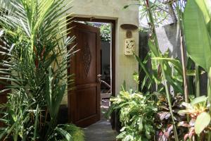 une porte en bois ouverte dans un jardin orné de plantes dans l'établissement Belle Asana, à Canggu