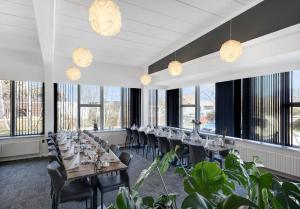 una sala da pranzo con tavoli, sedie e finestre di Østergaards Hotel a Herning