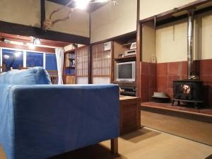 a living room with a blue couch and a television at Twinkle Villa in Kokuryō