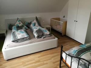 ein Bett mit Kissen und ein Kinderbett in einem Schlafzimmer in der Unterkunft C1 Schwarzwald-Fewo an der Alb 50m FerienwohnungApp für max 5 Personen in Menzenschwand