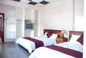 a hotel room with two beds and a tv at New Sleep in Dalat Hostel in Da Lat