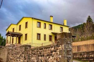 una casa amarilla en la parte superior de una pared de piedra en Baldeneige, en Pramanta