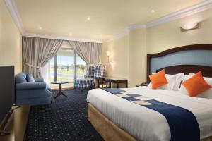 Howard Johnson Dammam Hotel في الدمام: غرفه فندقيه بسرير وكرسي