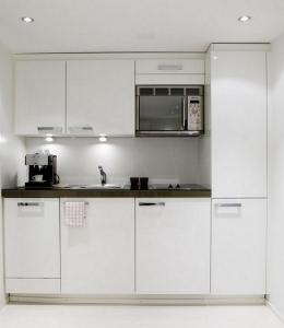 a kitchen with white cabinets and a microwave at VISIONAPARTMENTS Binzmühlestrasse 48 - contactless check-in in Zurich