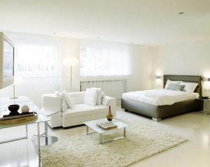 een witte slaapkamer met een bed en een bank bij VISIONAPARTMENTS Binzmühlestrasse 48 - contactless check-in in Zürich