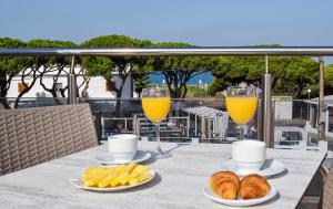 two glasses of orange juice and croissants on a table with drinks at Aparthotel Novo Sancti Petri in Chiclana de la Frontera