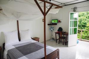 a bedroom with a bed and a desk and a television at Hotel Jardin de la Paix in Moroni