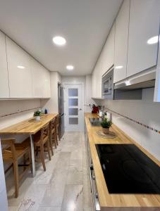マラガにあるApartamentos Prestige Suites Málaga IIIの白いキャビネットと木製テーブル付きのキッチン