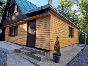 una pequeña casa de madera con un árbol delante en Chata Tokarka - Richňavské jazerá en Štiavnické Bane