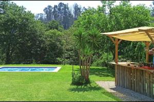 a backyard with a swimming pool and an umbrella at A Viña de Lina. Turismo rural con piscina y finca. in Pontevedra