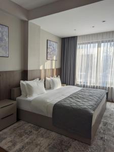 a bedroom with a large bed and a large window at Raavah Aparthotel in Almaty