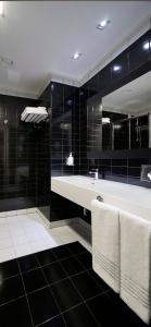 a bathroom with a white tub and black tiles at voco Nola - Naples Vulcano Buono by IHG in Nola