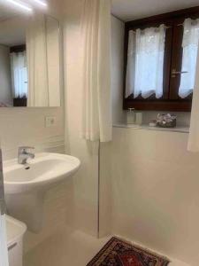 a bathroom with a sink and a toilet and a mirror at Pinzolo, grazioso appartamento, wellness a 100 metri in Pinzolo