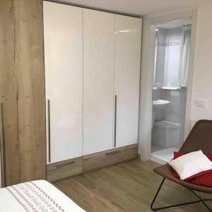 ein Schlafzimmer mit weißen Schränken, einem Bett und einem Stuhl in der Unterkunft Pinzolo centro, grazioso appartamento in Pinzolo