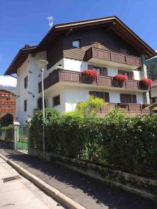 a building with red flowers on the balconies on it at Pinzolo, grazioso appartamento, wellness a 100 metri in Pinzolo