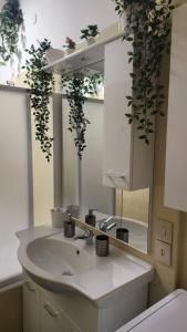 een badkamer met een wastafel en een spiegel met planten bij DEA DREAMS San Siro 27 Apartment in Milaan