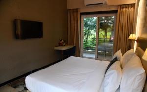 a bedroom with a large white bed with a window at Gandharv Resorts in Wai