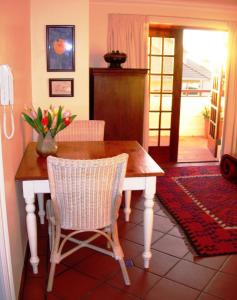 a dining room table with a vase of flowers on it at Bakoven Cottage in Cape Town