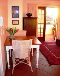 una mesa de comedor con un jarrón de flores. en Bakoven Cottage, en Ciudad del Cabo