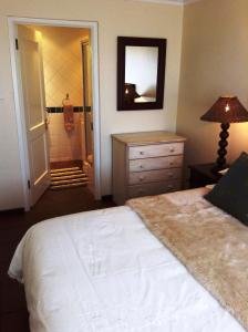 a bedroom with a bed and a dresser and a mirror at Bakoven Cottage in Cape Town