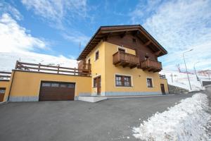 リヴィーニョにあるSole Ski in- Ski out Mt 50 - Happy Rentalsの雪の中のガレージ付き黄色い家