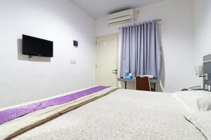 1 dormitorio con 1 cama y TV en la pared en Paus Guest House Pekanbaru en Pekanbaru