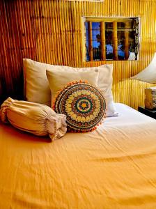 a bed with a pillow and pillows on it at Balai Consuelo Pamingwitan Campground in Buliran