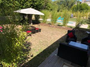 eine Terrasse mit einem Tisch, Stühlen und einem Sonnenschirm in der Unterkunft Domaine Plessis Gallu - vacation cottage rental in Azay-le-Rideau