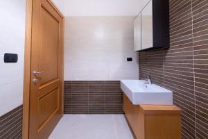 La salle de bains est pourvue d'un lavabo blanc et de carreaux bruns. dans l'établissement Casa Titty, à Rome