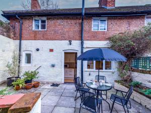 a patio with a table and chairs and an umbrella at Pass the Keys Cosy 2 bedroom Victorian Cottage in Ludlow