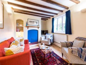 a living room with a red couch and chairs at Pass the Keys Cosy 2 bedroom Victorian Cottage in Ludlow