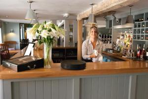 a woman standing behind a counter in a bar at Meddlars a historic cottage on the countryside edge of a vibrant Market Town in Hadleigh