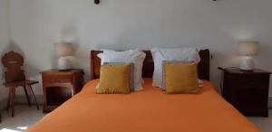 a bed with orange sheets and yellow pillows on it at La maison horlogère , spas et bain nordique in Les Fontenelles