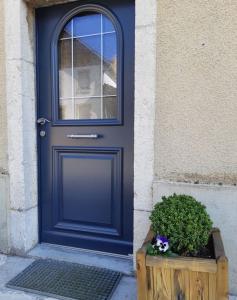 une porte bleue avec une plante dans une boîte en bois dans l'établissement La maison horlogère , spas et bain nordique, à Les Fontenelles