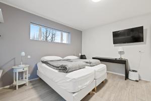 a white bedroom with a bed and a tv at Acco Guesthouse in Akureyri