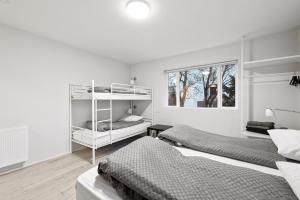 a white bedroom with two beds and a window at Acco Guesthouse in Akureyri