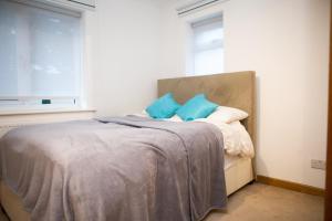 a bedroom with a bed with blue pillows and a window at 2 Double bedroom House in Harrow