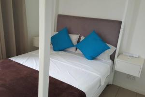 a bedroom with a bed with blue pillows on it at Lovely 3-bedroom at Azuri Ocean & Golf village in Roches Noires