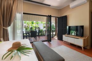 a bedroom with a bed and a television and a patio at Sea&Sky Beach Resort Beachfront Bungalows & Pool Villas in Mae Nam